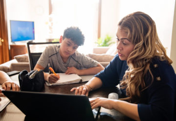 Mom at home with two kids trying to help them with online work.