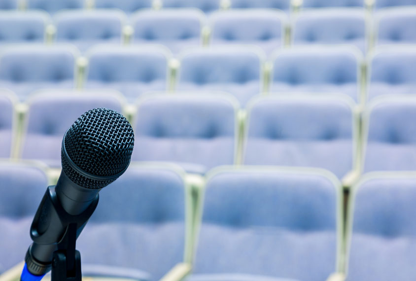 Empty conference room with closeup of microphone in foreground.